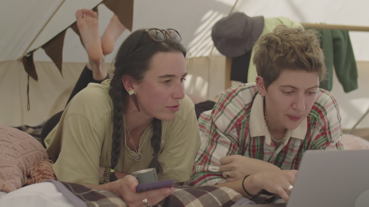 Two Girls Resting in Glamping Tent and Using Laptop