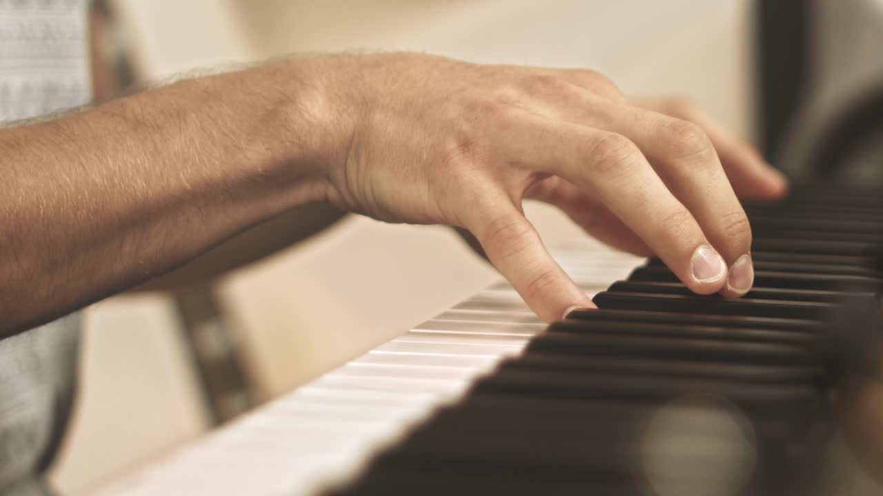 primer plano de un pianista profesional tocando e improvisando en un piano de escenario durante una sesión de grabación con un fondo brillante