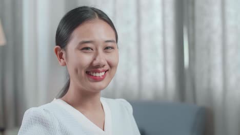 집에서 데스크에서 일하는 동안 미소 짓고 카메라에 팔을 는 하우스 모델과 함께 아시아 여성 엔지니어의 클로즈업