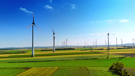 rising over the green field on sunny day. multiple windmills rotate producing clean energy.