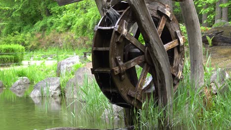 rueda de agua de madera colocada cerca de un pequeño lago en el parque namsan con bosque verde en la montaña namsan en seúl, corea del sur