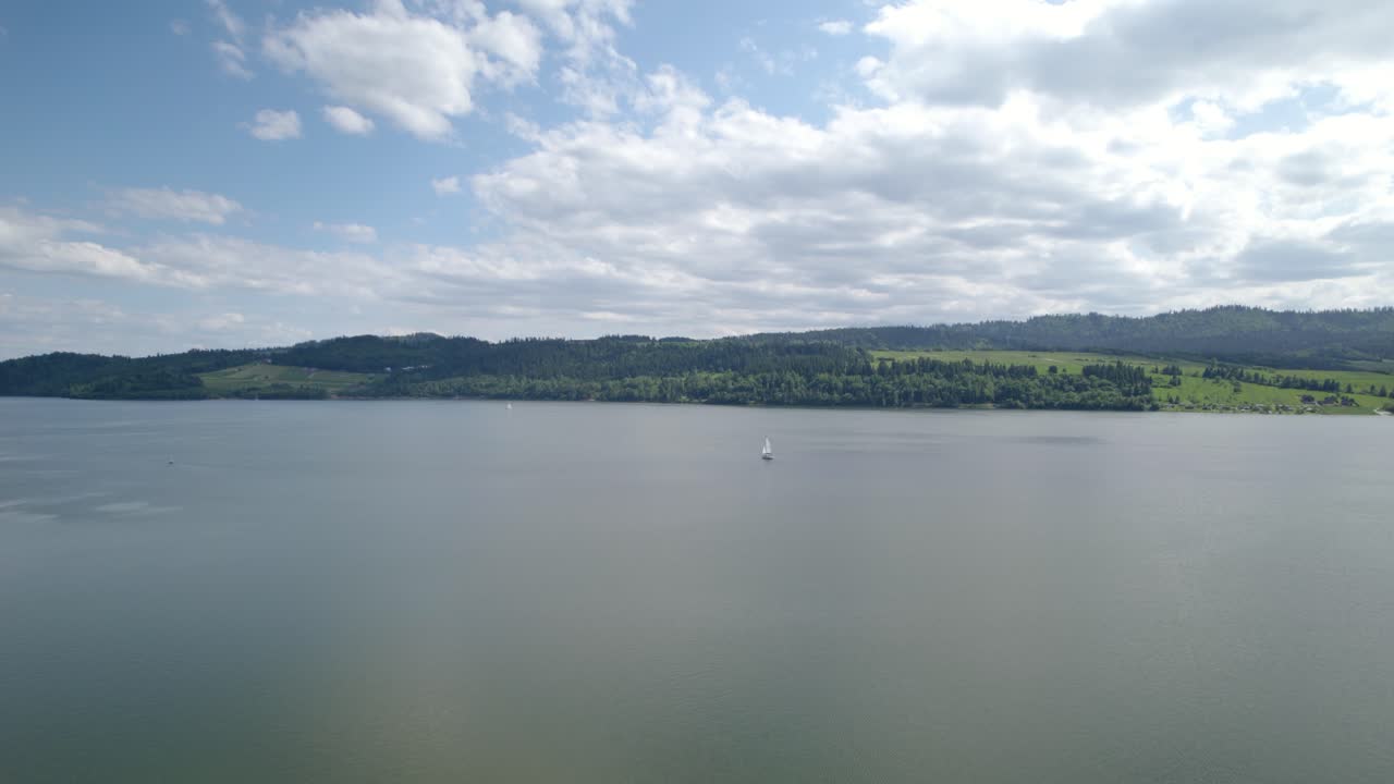 구름이 많은 날 호수 한가운데에 있는 작은 외로운 배의 공중 촬영