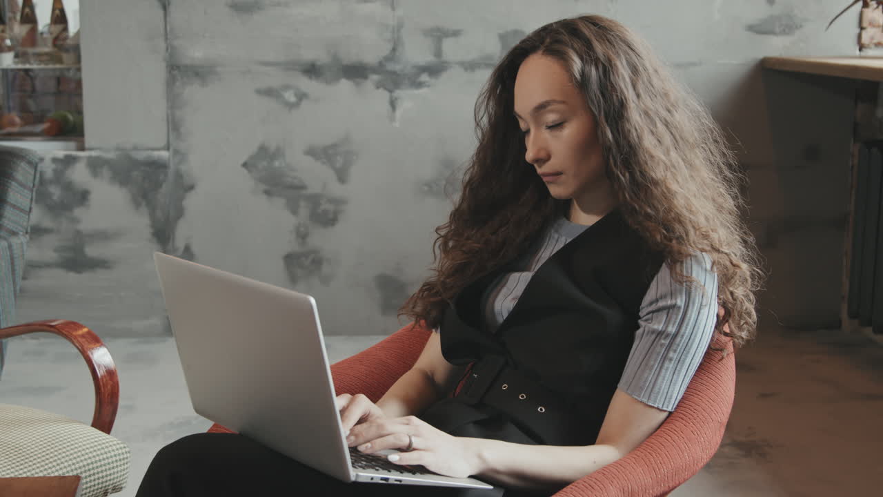 Young Mixed-Race Woman Working on Laptop in Contemporary Workspace