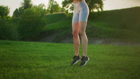 a woman jumps up and squats in the park at sunset. training a young woman on the street in the park