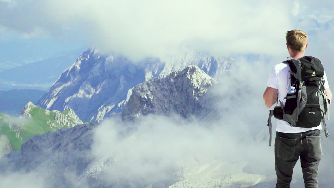 배낭을 메고 있는 백인 청년은 알프스에서 탁 트인 전망을 즐긴다