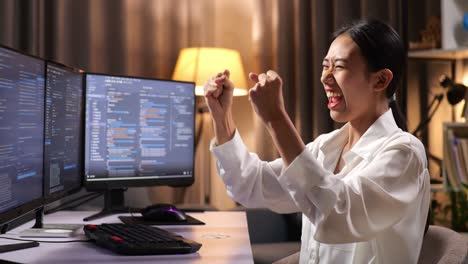 mujer programadora asiática celebrando el éxito en la creación de ingeniero de software desarrollando aplicaciones, programas, videojuegos en computadora de escritorio en casa. terminal con lenguaje de codificación