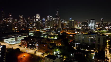 aerial view backwards over the cityscape of river west, night in chicago, usa