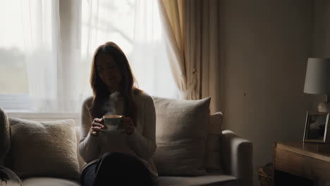 woman relaxing with hot drink by the window