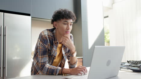 using laptop, teenage boy in casual attire working from home office