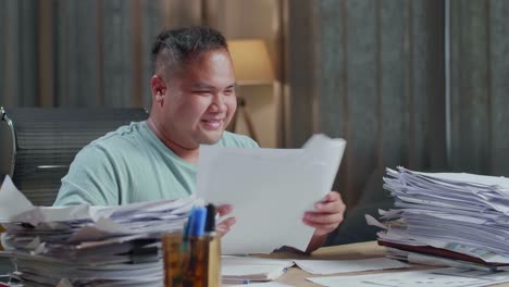 close up of happy fat asian man throw away the paper and celebrating finishing working with documents at the office