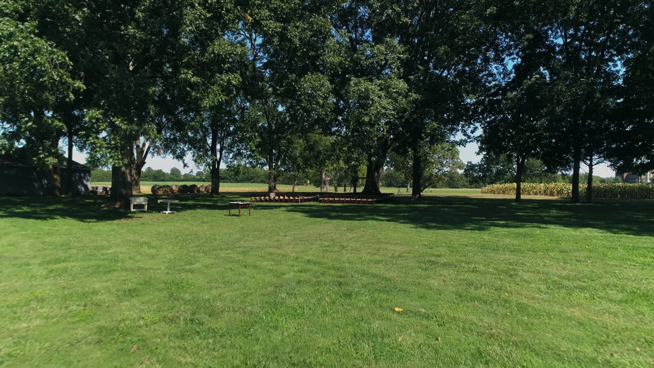 Low drone aerial approaching beautiful wedding alter under large tree, 4K