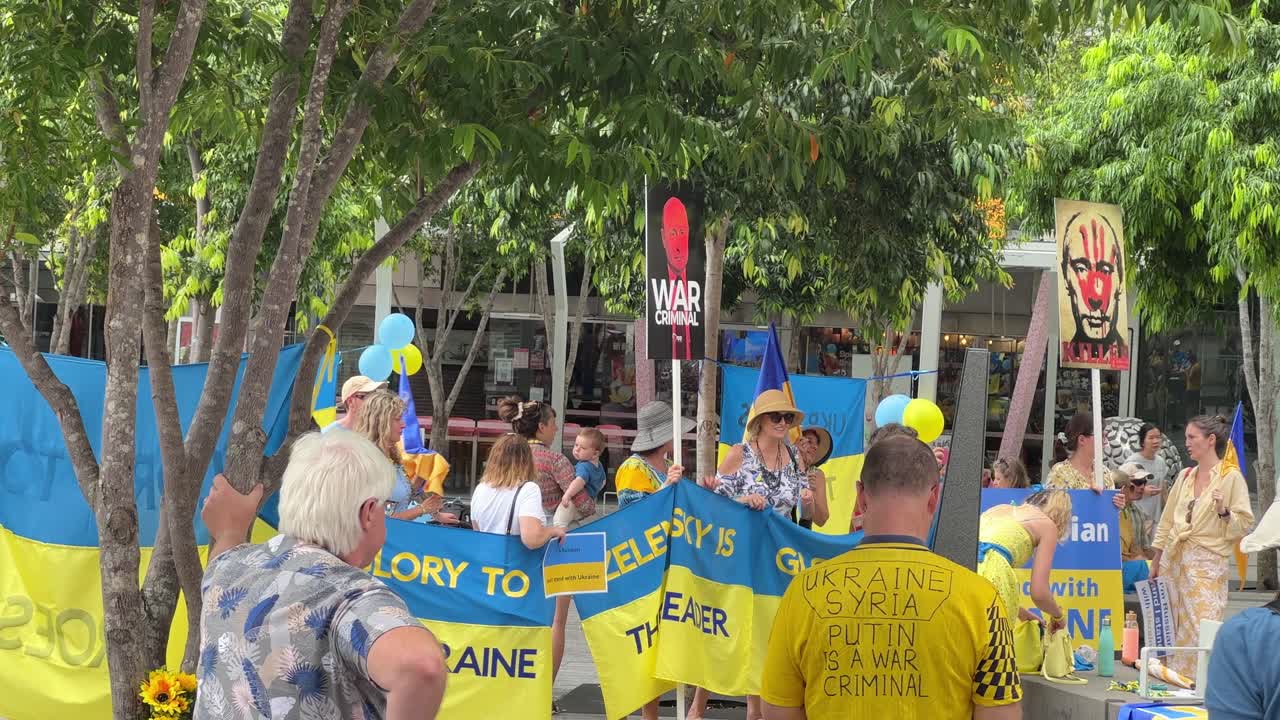 Panning shot of a big group of protesters gathered at Brisbane Square raising and wearing Ukraine flags while condemning the inhumane Russian Special Military Operation happening at Ukraine.