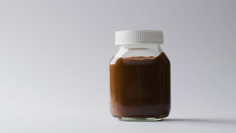 video de primer plano de un frasco de crema de chocolate sobre un fondo blanco