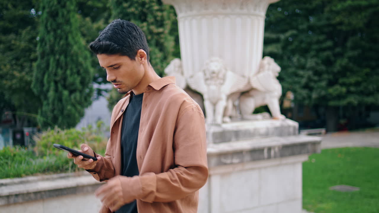 진지한 남자가 드폰 메시지를 듣고 수직으로 주차합니다. 전화를 들고 있는 사업가