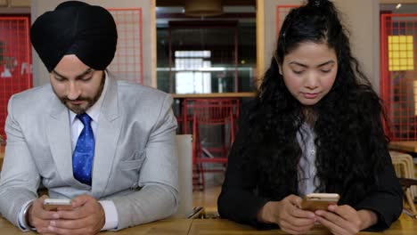pan left to right and back on four indian colleagues busy transfixed on their smart phone mobile screen devices as they chat, text and surf using wifi internet communication