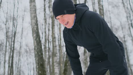 A-young-man-on-a-morning-jog-in-the-winter-forest-was-tired-and-stopped-to-rest-and-ran-on.-He-recovered-his-strength-and-overcame-fatigue-and-continued-to-run.-Perseverance-and-overcoming-weakness.-Striving-forward.-Slow-motion.-Healthy-lifestyle