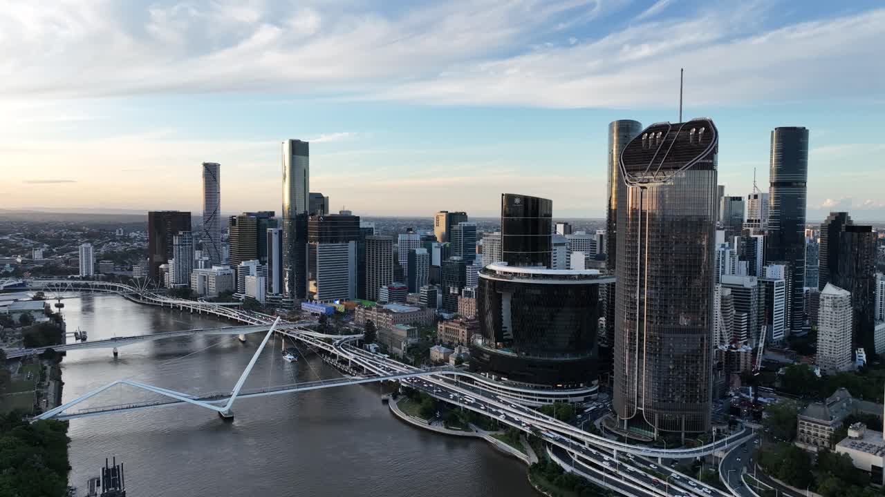 Langsom dronning panorering mod højre ved den gyldne time langs Brisbane-floden, der fremviser Queens Wharf og The Star Brisbane-tårnene med Neville Bonner Bridge og forretningskvarterets skyline, Brisbane, QLD, Australien