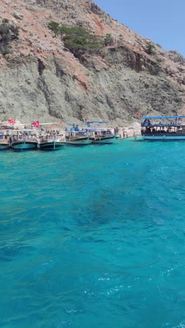 a group of boats are docked in the water near a rocky shore