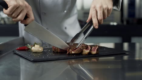 las manos del chef cortando bistec en la cocina del restaurante