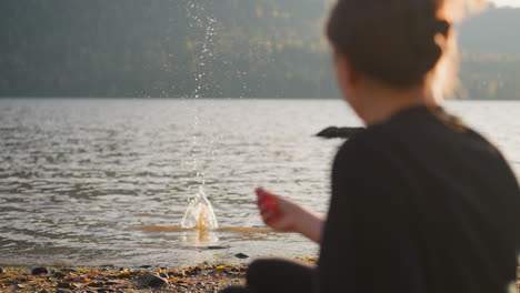 woman sitting by a lake in the mountains