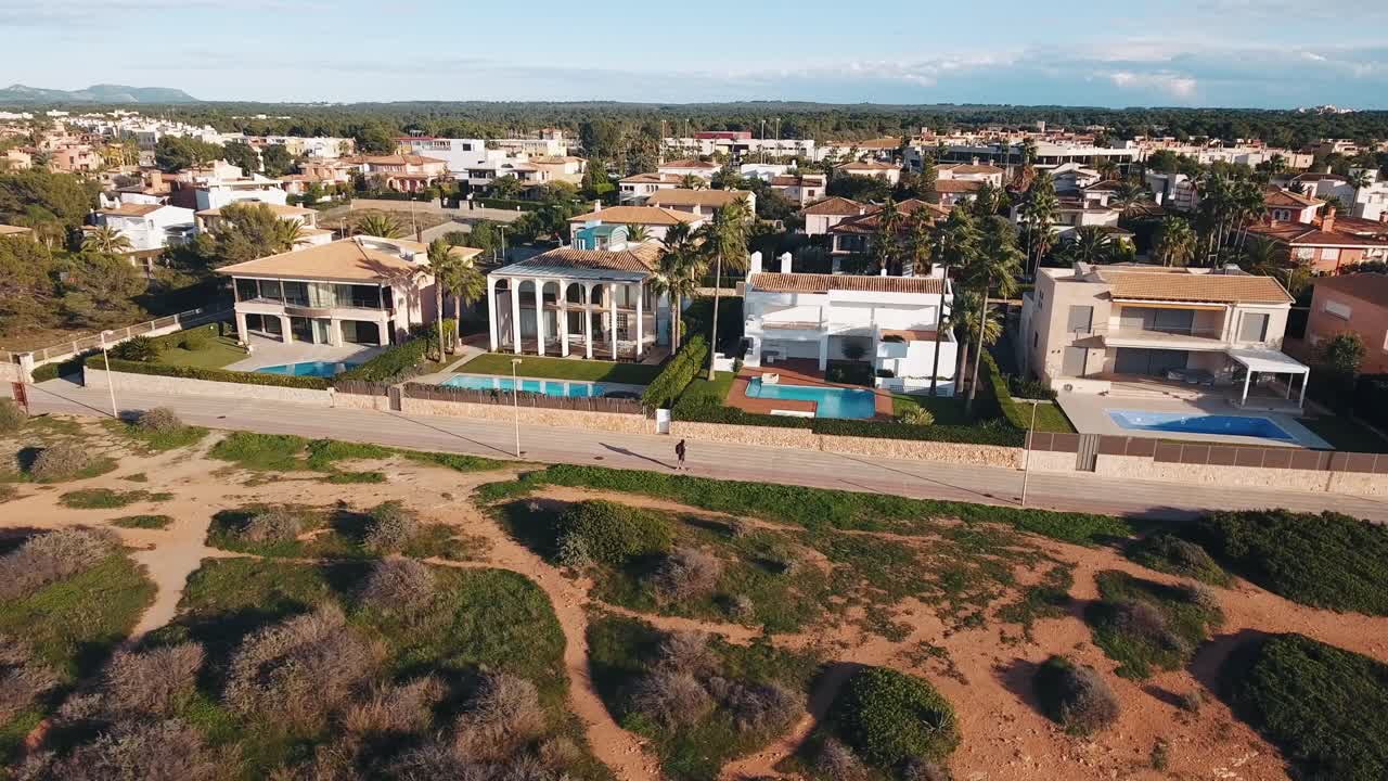 impresionantes imágenes aéreas de una persona en una patineta - longboard frente a hermosas propiedades inmobiliarias de lujo en mallorca, españa