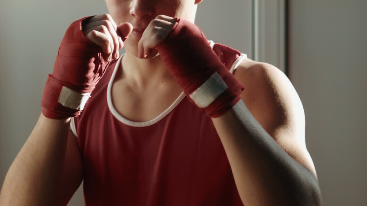 The Young Boxer Pulls Red Bandage on Hands