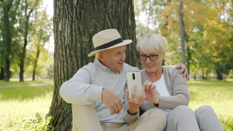 senior couple enjoying time in the park with smartphone