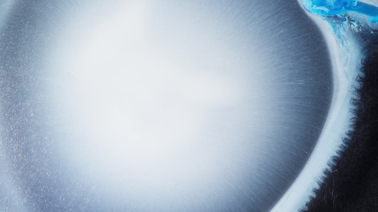 Alcohol ink forming bright circular bloom in abstract macro composition