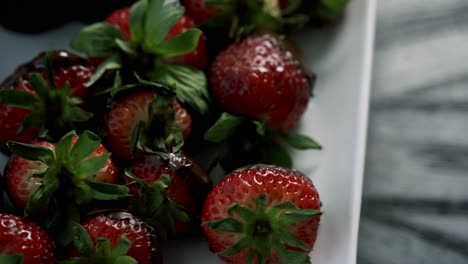 top aerial view of chocolate covered strawberries rotating on a white plate