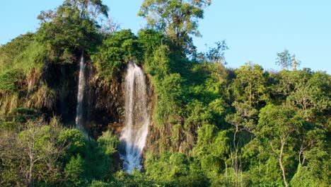 La-Cascada-Natural-Que-Fluye-Por-La-Montaña-Está-Iluminada-Por-El-Sol-Vespertino