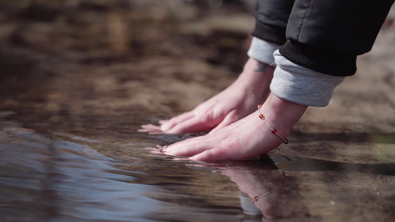 Women washing hand in cold lake, outdoor activities