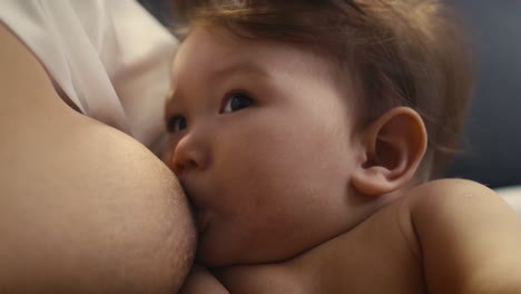 primer plano extremo del bebé asiático amamantado por la madre