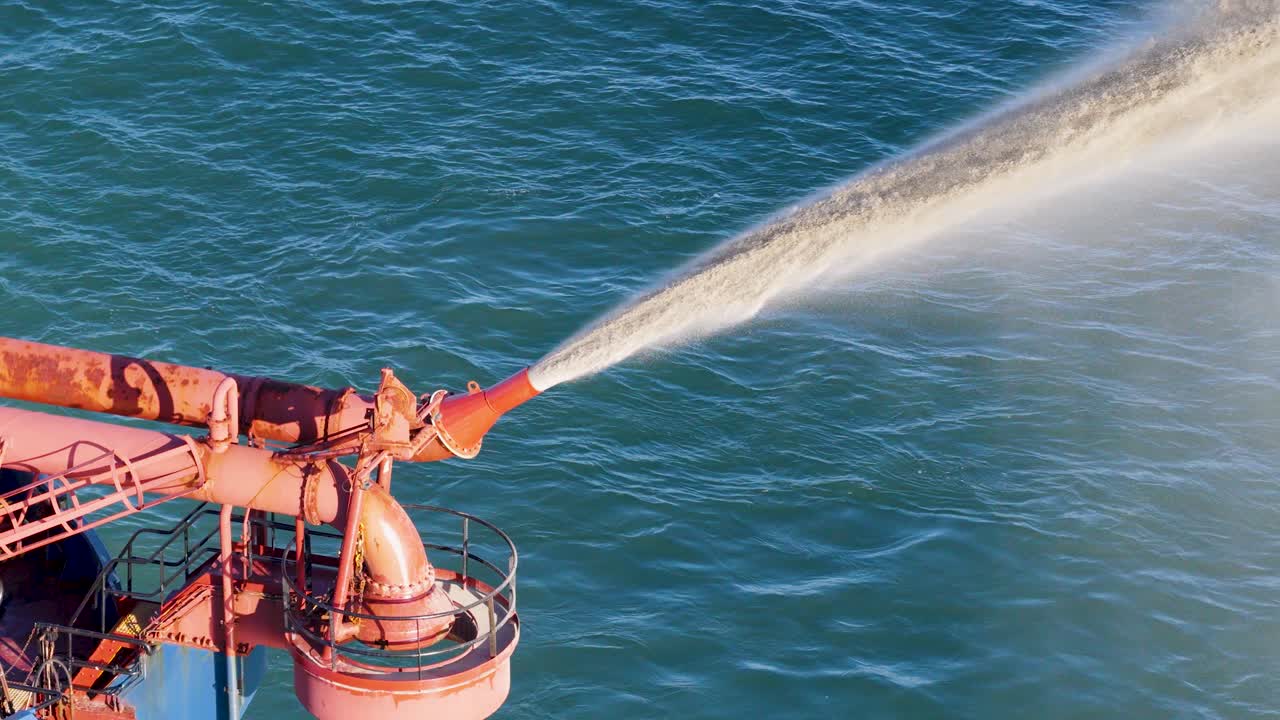 A dredging machine pumps sand into the ocean, combating erosion under clear skies on the Gold Coast