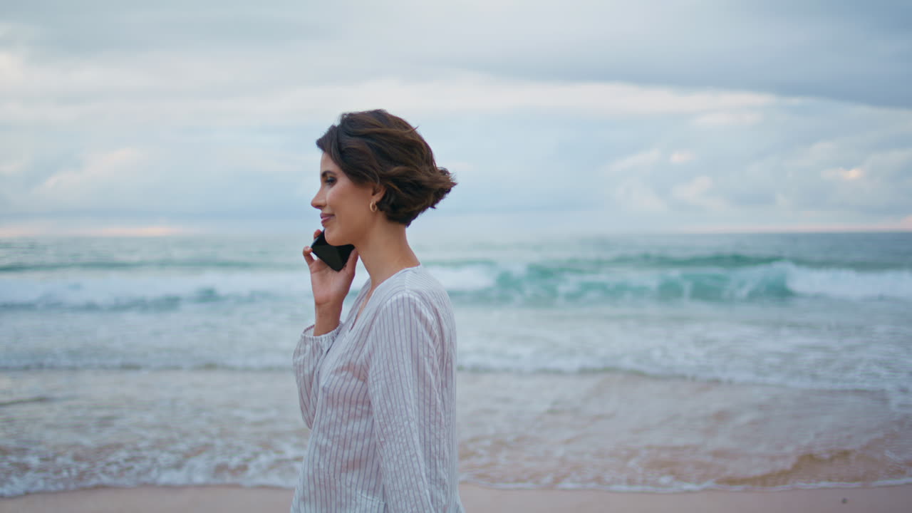 바다의 파도에서 휴대 전화 대화를 즐기는 여성. 평온한 모델 해변을 걸어