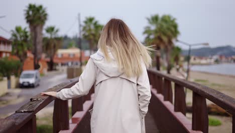 Blonde-woman-walking-on-small-wooden-bridge-in-a-small-city