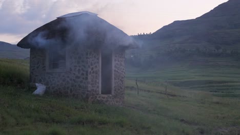 cook fire smoke billows from small stone guard shack in lesotho africa