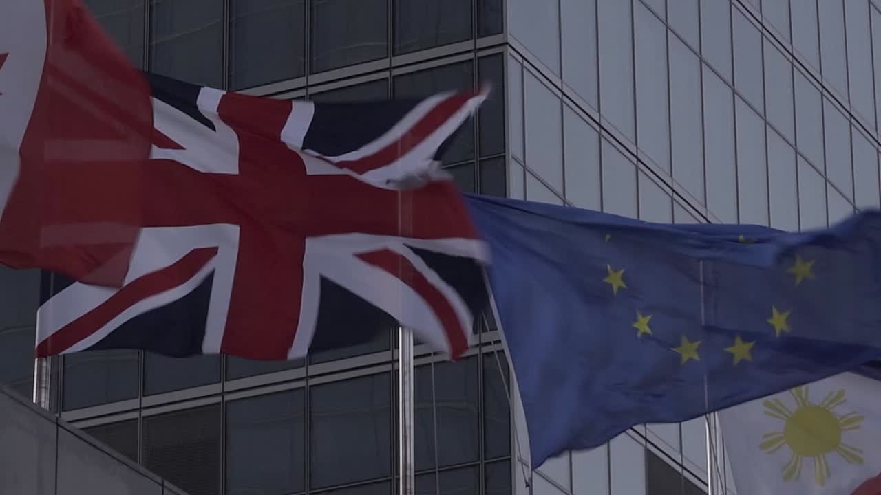 union jack del reino unido y bandera de la unión europea en un día tormentoso y ventoso contra el brexit del centro de negocios