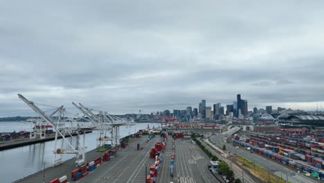 wide aerial view of seattle's vacant shipyard with clouds and city skyscrapers in the distance