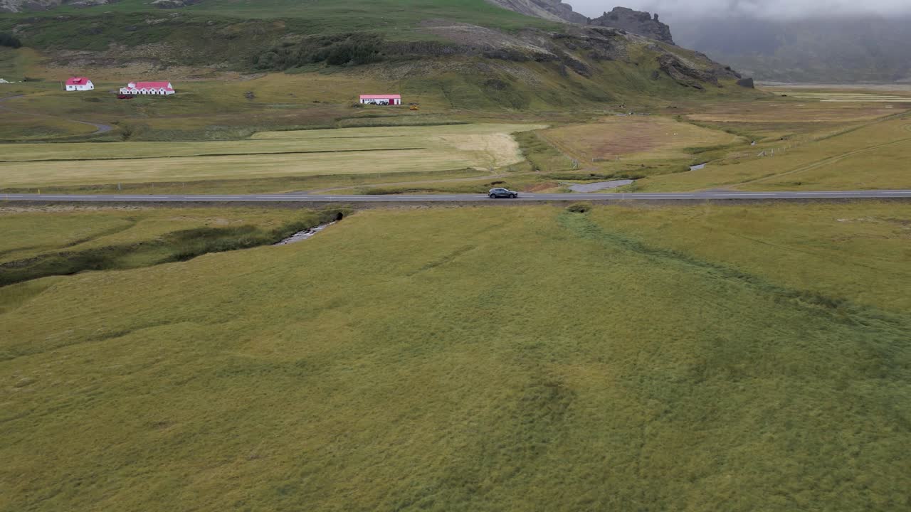 Traverse Iceland's scenic expanses with this captivating 4K drone footage, featuring a unique arial view as a car drives through the bare countryside of Iceland