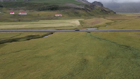 Traverse-Iceland's-scenic-expanses-with-this-captivating-4K-drone-footage,-featuring-a-unique-arial-view-as-a-car-drives-through-the-bare-countryside-of-Iceland