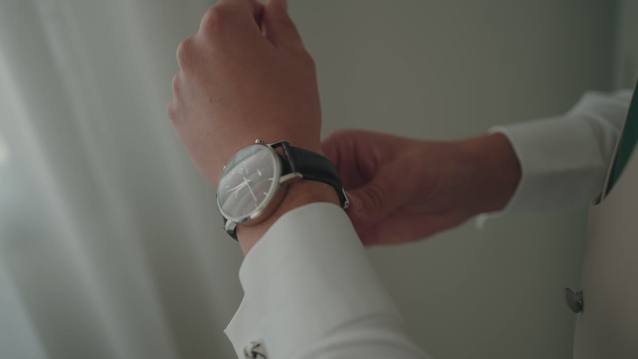 Close view of hands fastening a wristwatch strap in gentle indoor light