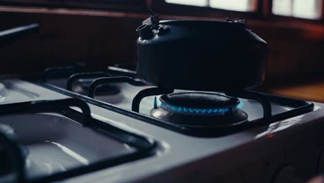 a person ignites the stove to heat a kettle in a kitchen in reinsjøen, åfjord, trøndelag, norway - close up