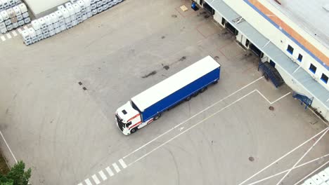 Aerial-circling-view-of-a-logistics-center-with-warehouse,-loading-hub-with-many-semi-trailers-trucks-load-unload-goods-at-sunset