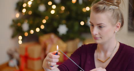 Young Woman Igniting Sparkler With Lighter At Home