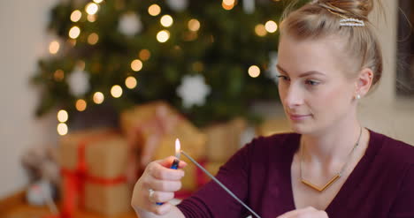 young woman igniting sparkler with lighter at home