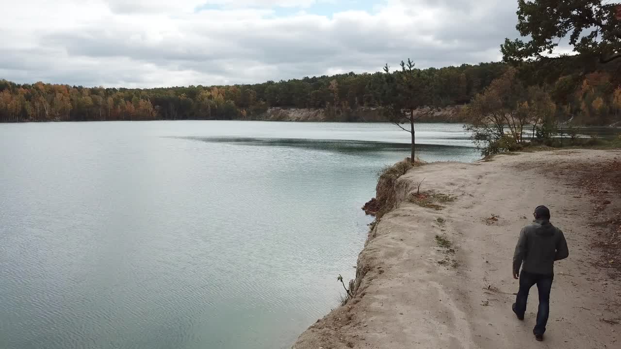 Man walking on nature. Aerial view of adult man walking near forest with lake