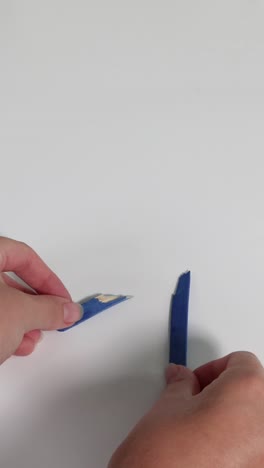 hands break a blue pencil into two pieces