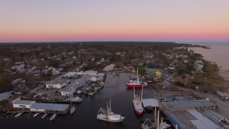 aerial drone flyover of oriental nc harbor and town docks at sunset forward flight with diesel spill facing north