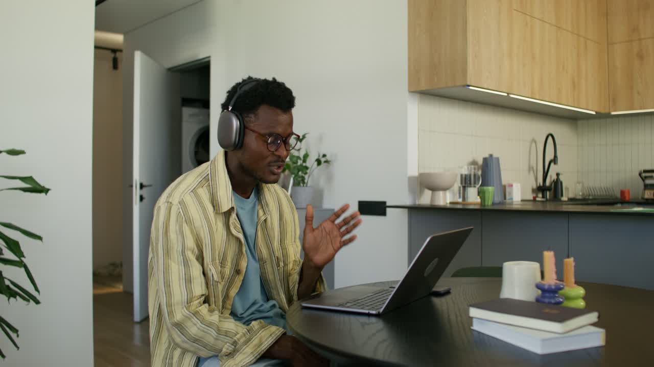 Man in headphones having a video call in his kitchen