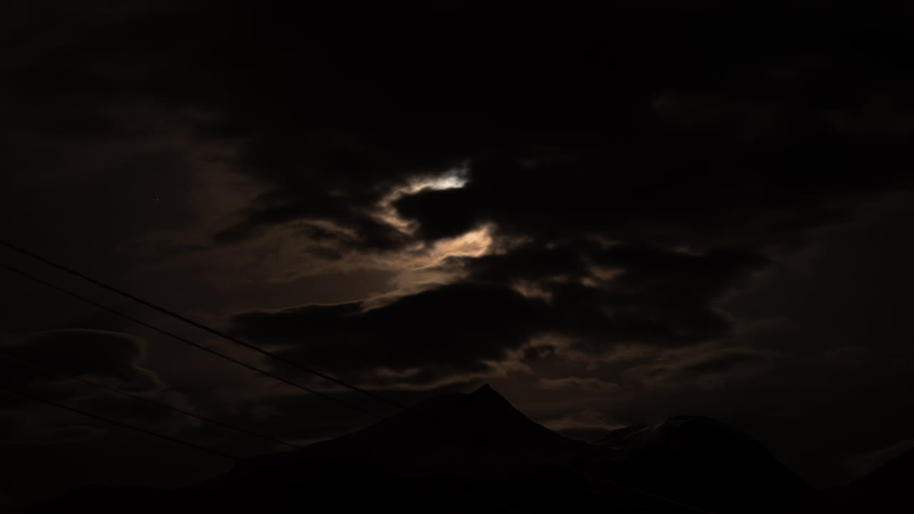 Timelapse delle nuvole che si muovono davanti e coprono una luna luminosa e splendente nell'oscurità.